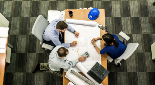 three people at table with laptop and blueprints