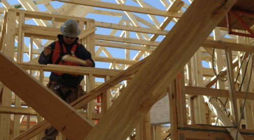 Construction worker checks for excess timber framing in house under construction