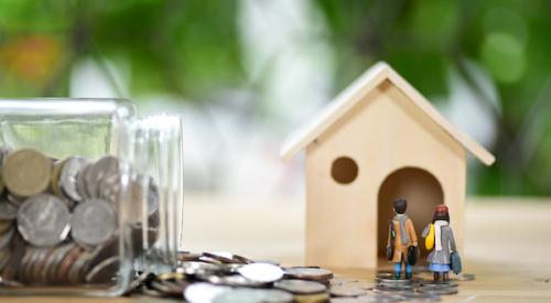 tiny home model with glass jar of coins laying on its side with coins spilling out 