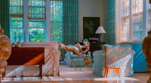 House interior with woman reading book on sofa