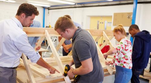 High school students building in wood shop classroom