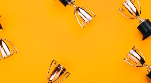 Golden trophies against orange background for winning a competition