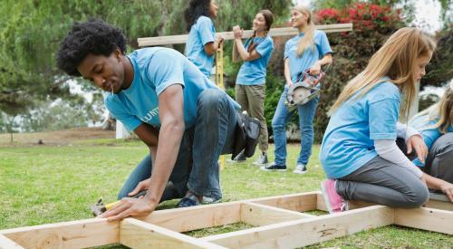 Volunteers lift house frame