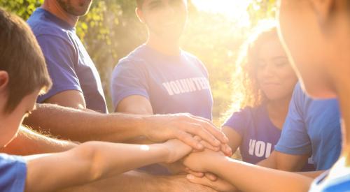 Volunteers standing with hands together