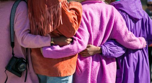 Women hugging with brightly colored coats on