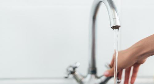 Person turning on kitchen faucet