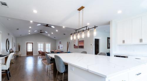 White modern kitchen with island seating in open concept living area