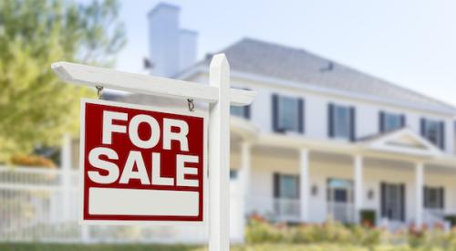 for sale sign out front of two-story home with black shutters