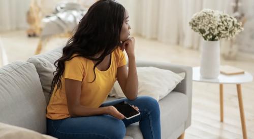 Woman sitting on sofa looking worried during pandemic