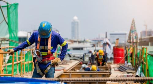 Construction worker in harness on roof of building