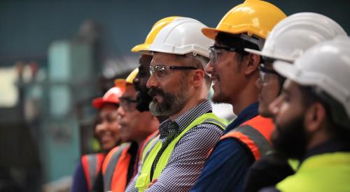 Row of construction workers wearing hard hats and vests