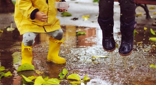 Kids in rain boots splashing in a puddle