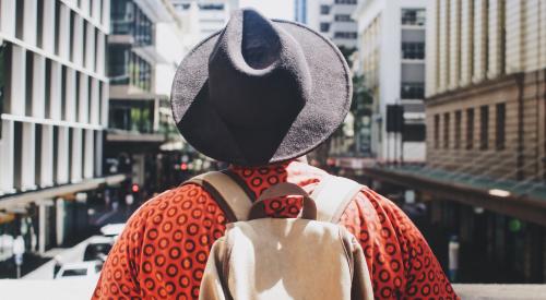 Man with backpack on facing city street